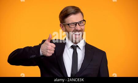 Glücklicher Mann in Anzug, Daumen hoch und zwinkerte Kamera, gutes Angebot Stockfoto