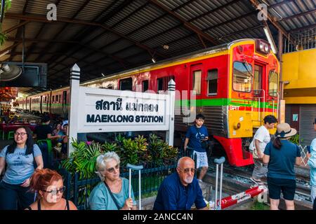 Mae Klong/Thailand-08December2019: Mae Klong Bahnhof mit Gleisen und Zügen, die durch den täglichen Markt führen, mit Anbietern, die alles verkaufen. Stockfoto