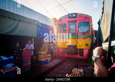 Mae Klong/Thailand-08December2019: Mae Klong Bahnhof mit Gleisen und Zügen, die durch den täglichen Markt führen, mit Anbietern, die alles verkaufen. Stockfoto