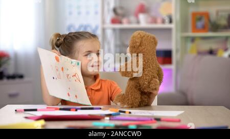 Lächelnde Mädchen zeigt Zeichnungen Teddybär, Spielzimmer Freizeitaktivitäten, imaginären Freund Stockfoto