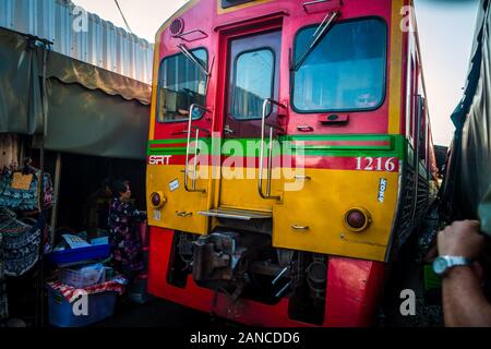 Mae Klong/Thailand-08December2019: Mae Klong Bahnhof mit Gleisen und Zügen, die durch den täglichen Markt führen, mit Anbietern, die alles verkaufen. Stockfoto