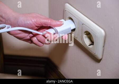 Close-up Frau die Hand Stecker in die Steckdose. Weibliche hand ausstecken Stockfoto