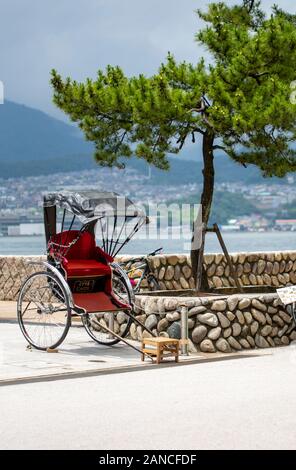 Rikscha in der Nähe von Itsukushima Schrein, ein Shinto Schrein und UNESCO-Weltkulturerbe auf der Insel Miyajima. Stockfoto