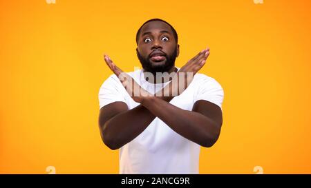 Afro-amerikanischen jungen Mann mit STOP-Schild durch die Hände auf gelben Hintergrund, Warnung Stockfoto