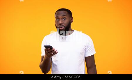 Betäubt, junge Mann mit Smartphone in der Hand, Banking, Cash back Stockfoto