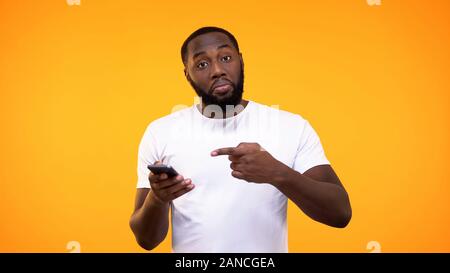 Junge afro-amerikanischer Mann an Smartphone zeigt in der Hand, eine Empfehlung, Anwendung Stockfoto
