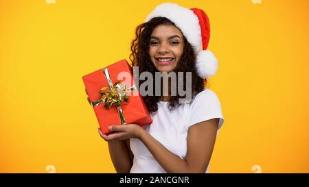 Freundliche attraktive Frau in santa claus Hut mit roten Geschenkkarton und lächelnd Stockfoto