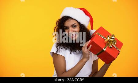 Fröhliche junge Frau in Santa Claus hat Betrieb vorhanden, lächelnd Kamera Stockfoto