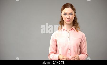 Rothaarige Frau in rosa Bluse in der Kamera auf grauem Hintergrund suchen, Vorlage Stockfoto