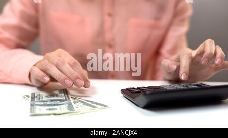 Weibliche Berechnung der monatlichen Ausgaben, Dollar, Banknoten auf Tisch, steuern die Zahlung Stockfoto