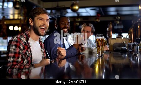 Multirassischen männliche Freunde feiern Sieg, Jubel für die lieblingsmannschaft in bar Stockfoto