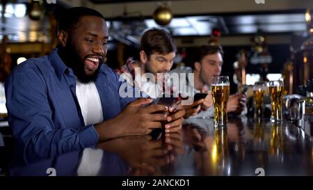 Afro-amerikanischer Mann feiert erfolgreiche Wette auf übereinstimmen, online Buchmacher auf Telefon Stockfoto