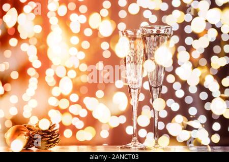 Zwei Gläser Champagner mit Weihnachten Spielzeug. Festliche Lichter bokeh Christmas background. Neujahr feiern. Horizontale, getönt, Rot zu Dunkel Braun, bold Licht bokeh Stockfoto