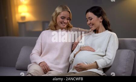 Lächelnd schwangere Frau mit Bauch, sitzt mit Freund, baby Erwartung Stockfoto