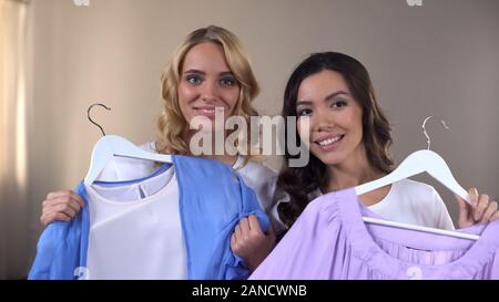 Zwei lächelnde weibliche Freunde Auswahl Kleidung in Shopping moll , Zimmer, Outfit Stockfoto