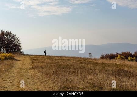 Silhouette eines Mannes, der in Bergen steht. Blauer Himmel Hintergrund Stockfoto