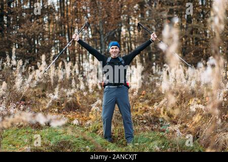 Portrait des glücklichen reifen Mannes mit Wanderstöcken im Herbstwald Stockfoto