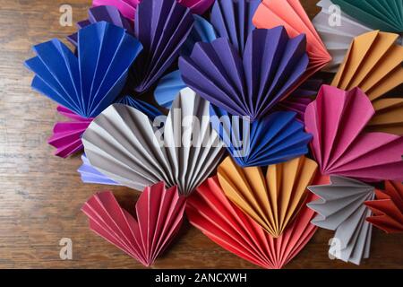 Mehrfarbige Origami-Herzen aus selbstgemachtem Papier auf einem Holztisch Stockfoto