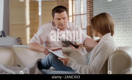 Böse Frau, Taschenrechner, um Mann, verheiratet Paar argumentieren über Familie Haushalt Stockfoto
