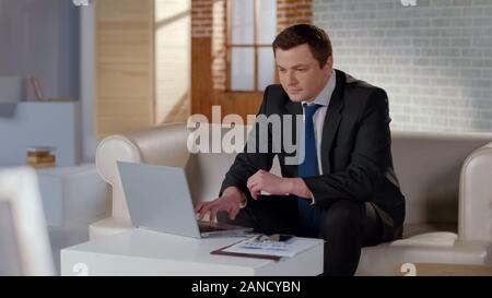 Positive Geschäftsmanns, der auf dem Laptop, mit dem Projekt zufrieden, Erfolg Stockfoto