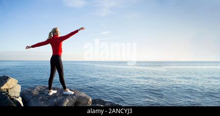 Junge Frau in Sportkleidung ihre Arme in der Luft gekleidet Stockfoto