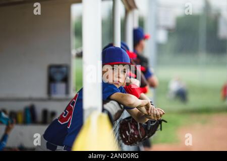 Junge in dugout während der kleinen Liga Baseball-Spiel Stockfoto