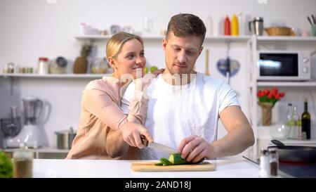 Mann Gemüse schneiden, liebevolle Frau umfing, romantischen Moment in der Küche Stockfoto