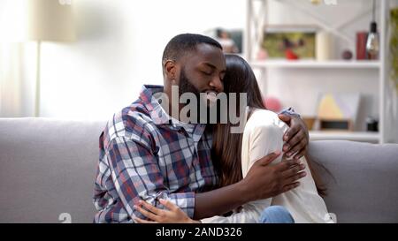 Happy multiethnischen Paar kuscheln auf dem Sofa zu Hause, der Friede nach Streit Stockfoto
