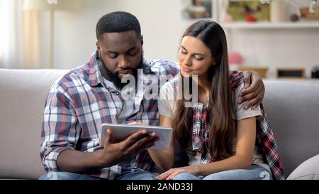 Jungen multiethnischen Paar mit Tablet-PC zu Hause, waren Sie online, Shopping Stockfoto