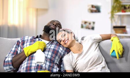 Multirassischen Familie in Handschuhe mit Reiniger Spray glücklich über Hausarbeit gemacht Stockfoto