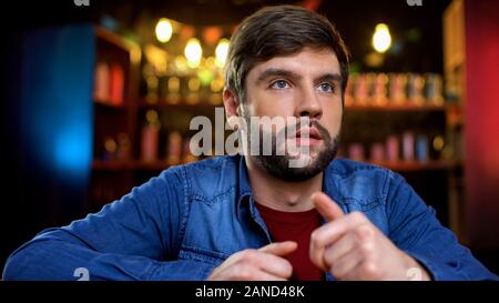 Junger Mann vor dem Fernseher sitzen an der Bar und warten auf Sport Nachrichten, Freizeit Stockfoto