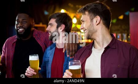 Kaukasische Freunde ihre afrikanischen amerikanischen Freund, trinken Bier in der Bar Stockfoto