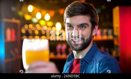 Schöne bärtige männliche klirren Biergläser mit Freund, Wochenende Ergebnisse im Pub Stockfoto