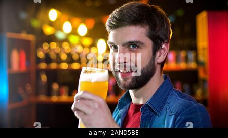 Lächelnd bärtiger Mann trinkt Bier, genießen, frischen Geschmack und Aroma von Handwerk Bier Stockfoto