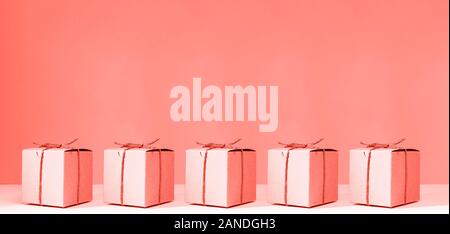 Handwerk Karton Geschenkboxen auf der soliden rosa Hintergrund. Urlaub, Geschenk, das Konzept. Pop Art slyle. Horizontale, wide screen Banner Format. Lebende Korallen Thema - Farbe für das Jahr 2019 Stockfoto