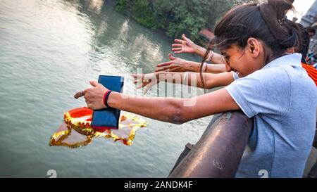 KOLKATA, West Bengal/INDIEN - Am 20. März 2018: In Howrah Bridge, indische Mädchen im Teenageralter werfen religiöse Angebote in den Hooghly River. Stockfoto