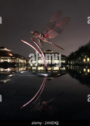 Dragonfly Skulptur am Hotelpool am Abend Stockfoto