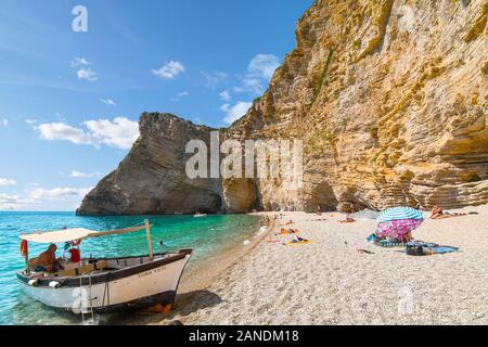Ein kleines Boot wartet am Sandstrand Touristen zurück in die Stadt von Paradise Beach zu transportieren, auch als Chomi Strand, auf der griechischen Insel Korfu bekannt Stockfoto
