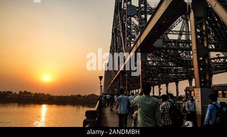 KOLKATA, West Bengal/INDIEN - Am 20. März 2018: In Howrah Bridge die Sonne wie Pendler und die Öffentlichkeit gleichermaßen der belebten Straße überqueren. Stockfoto