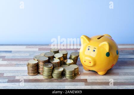 Nahaufnahme von Sparschwein und Goldmünzen auf dem Tisch Stockfoto