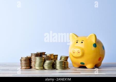 Nahaufnahme von Sparschwein und Goldmünzen auf dem Tisch Stockfoto