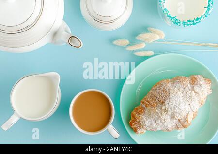 Frühstück Hintergrund. Frische Croissants auf Türkis Platten, Milch und Kaffee auf Pastell-blaue Tabelle. Ansicht von oben, flach Stockfoto