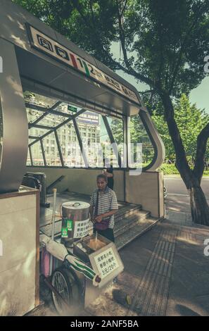 Chongqing, China - August 2019: älterer Mann verkaufen süße Snacks an einem heißen Tag am Eingang der Stadt u Stockfoto