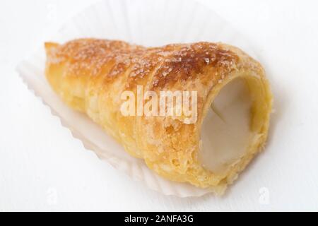 Blätterteig Horn mit Weiß Creme oder vla Susu auf einem weißen Hintergrund. Puff Horn mit Weiß Creme auf einem Spiegel Hintergrund gefüllt, close-up. Stockfoto