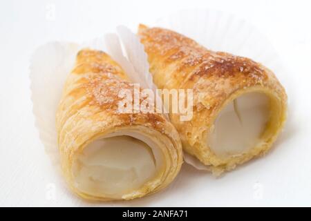 Blätterteig Horn mit Weiß Creme oder vla Susu auf einem weißen Hintergrund. Puff Horn mit Weiß Creme auf einem Spiegel Hintergrund gefüllt, close-up. Stockfoto