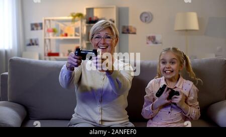 Lustig Oma und Mädchen spielen video game mit Konsole, voll Freude, Sieg, Hobby Stockfoto
