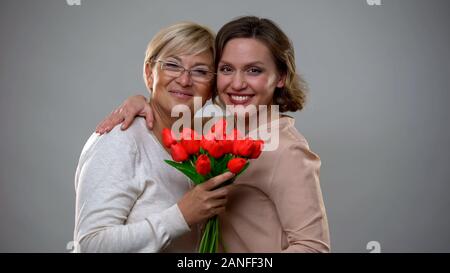 Fröhliche Mutter und Tochter lächelnd und Kamera, Tulpen Holding Stockfoto