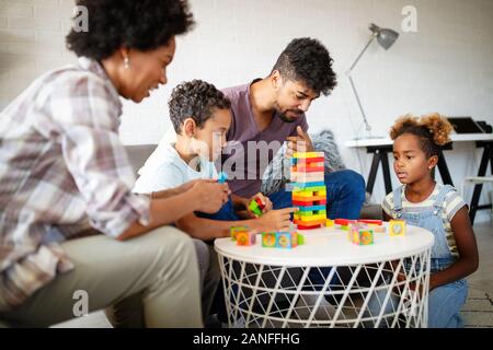 Zeit mit der Familie. Junge schwarze Eltern mit zwei Kindern zusammen zu Hause spielen Stockfoto