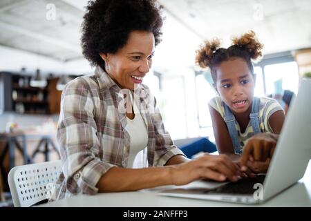 Glückliche Familie, Mutter und Kind Tochter zu Hause arbeiten auf dem Computer Stockfoto