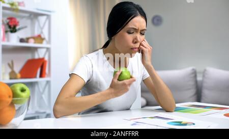 Junge Designer Gefühl Zahnschmerzen, grüner Apfel, der zu Hause arbeitet, Gesundheit Stockfoto